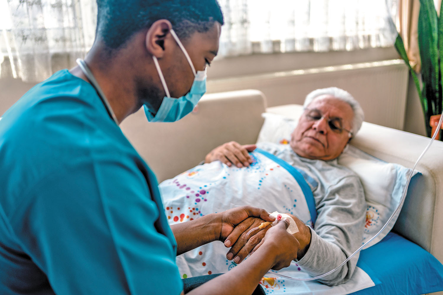 photo of a man laying on a couch in his home being attended to by a physician